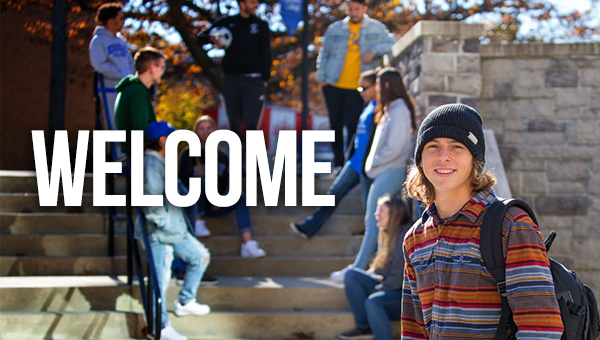 Welcome text overlaying image of one student smiling at the camera, with other students gathered behind on stairs